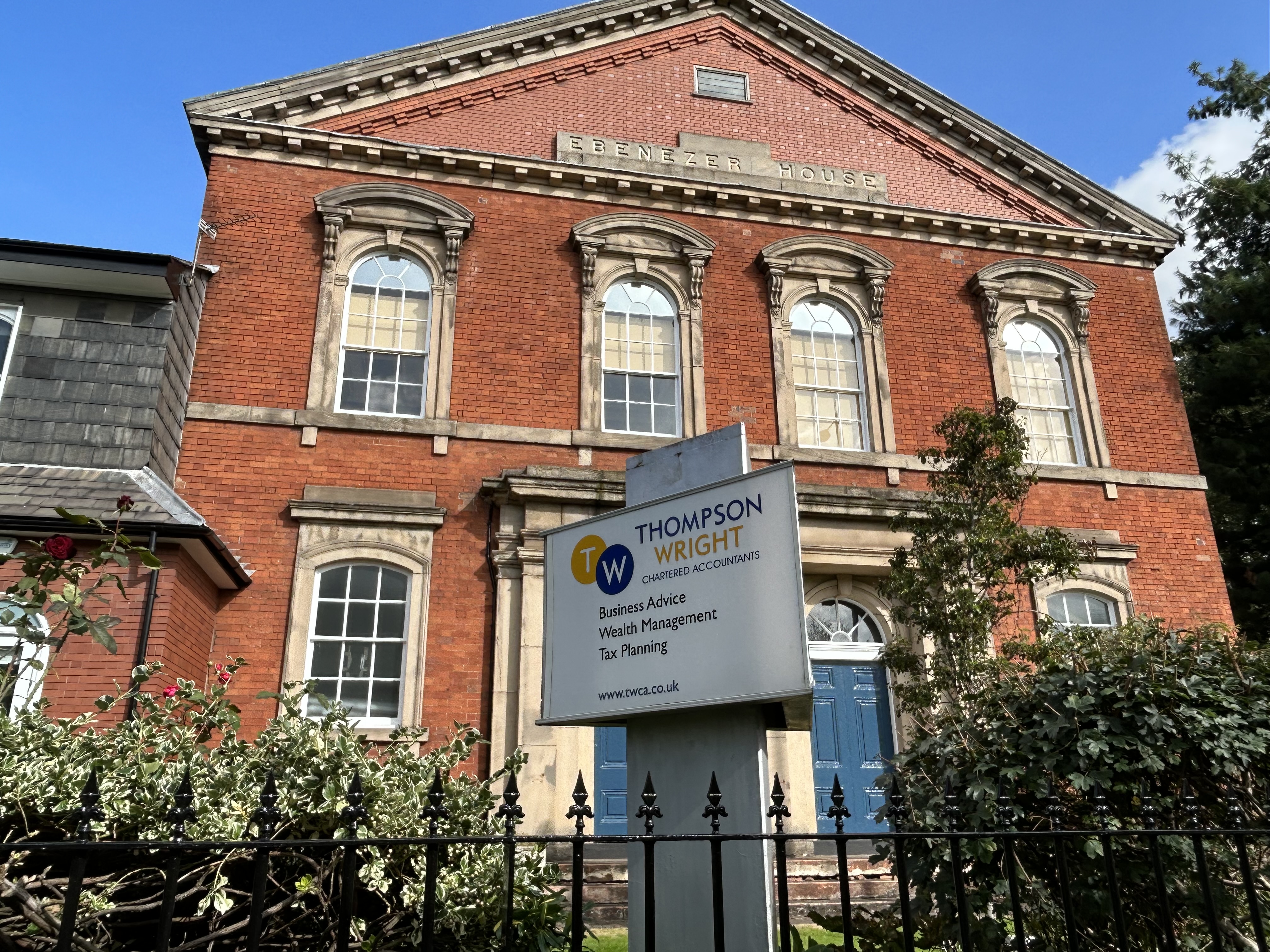 The exterior of a building with a sign for Thompson Wright Chartered Accountants