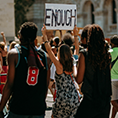 Image showing a woman holding a sign at a protest that reads 'enough'