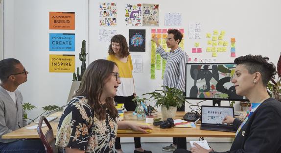 A photograph of five members of InFact Digital Co-op at work in their office.