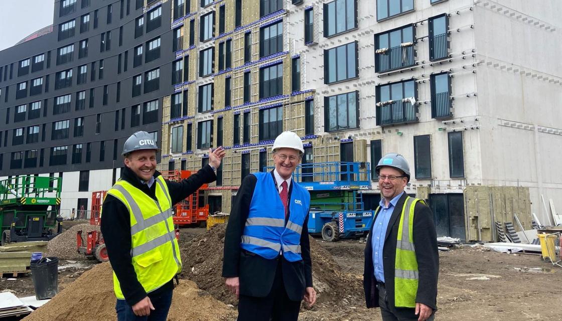Three men standing in front of a housing construction site