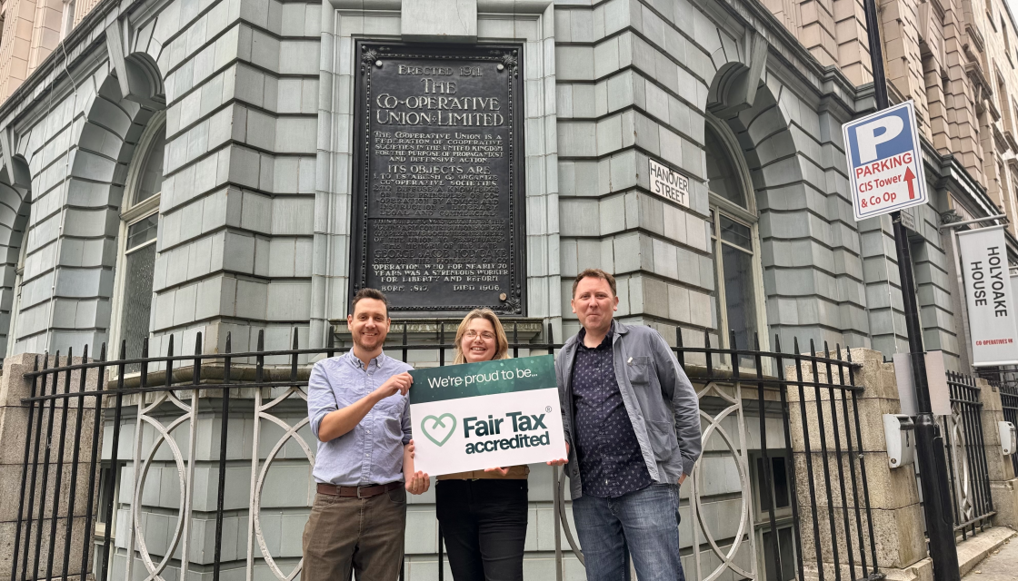 James Wright, Ruth Buchanan and Gareth Wright of Co-operatives UK stand in front of the Co-operatives UK office, Holyoake House, holding a sign that reads 'We are proud to be Fair Tax accredited.' 