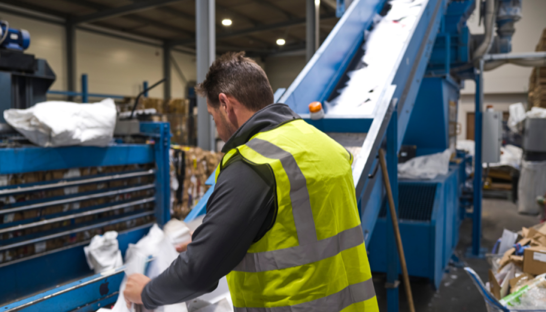 A man sorting recycling coming from a big machine