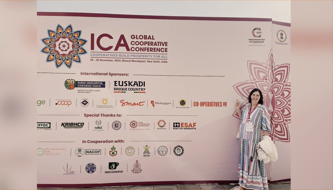 Rose Marley stood in front of a branded sign at the ICA Global Cooperative Conference 2024