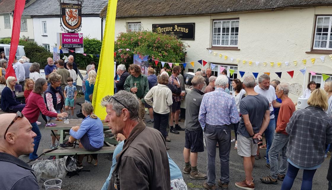 The exterior of The Drewe Arms with a crowd of people outside