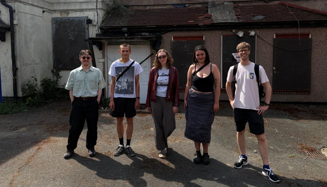 A group of young people in front of a derelict building