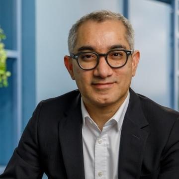 A photograph of One Family CEO, Jim Islam, sat down looking directly at the camera. 