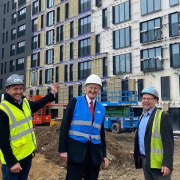 Three men standing in front of a housing construction site
