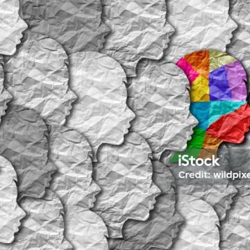 A collage of the profile of predominantly grey heads - in different shades - but with one head in a multicoloured jigsaw to illustrate neurodiversity and completely different ways of thinking. 