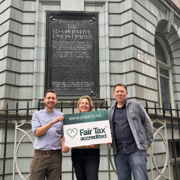 James Wright, Ruth Buchanan and Gareth Wright of Co-operatives UK stand in front of the Co-operatives UK office, Holyoake House, holding a sign that reads 'We are proud to be Fair Tax accredited.' 