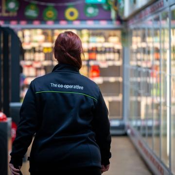 A photograph of a Chelmsford Star Co-operative colleague, in-store, walking away from the camera.