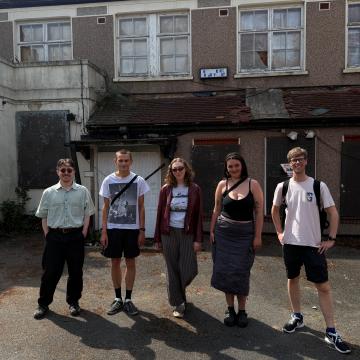 A group of young people in front of a derelict building