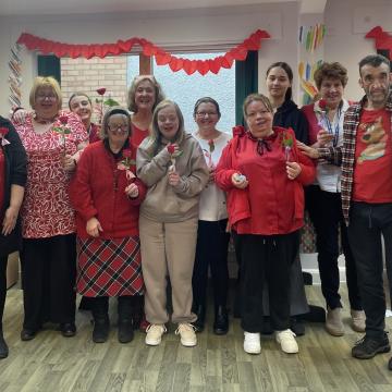 A Cartrefi Cymru group celebrates Valentine's Day: a row of people with hearts and flowers.